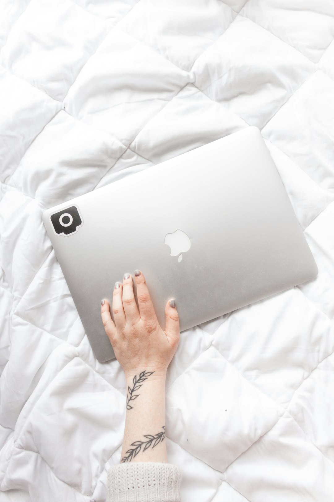 person holding silver macbook on white textile
