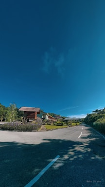A serene countryside path leading to cozy tiny houses surrounded by lush greenery under a clear blue sky.