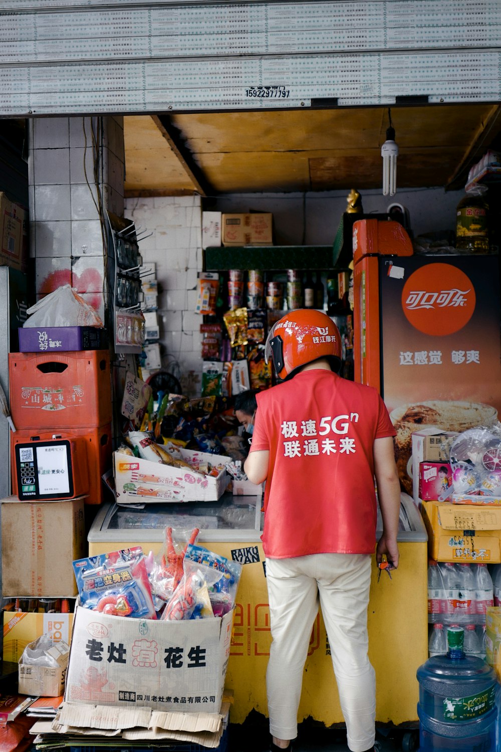 man in red crew neck t-shirt and beige pants standing near food packs