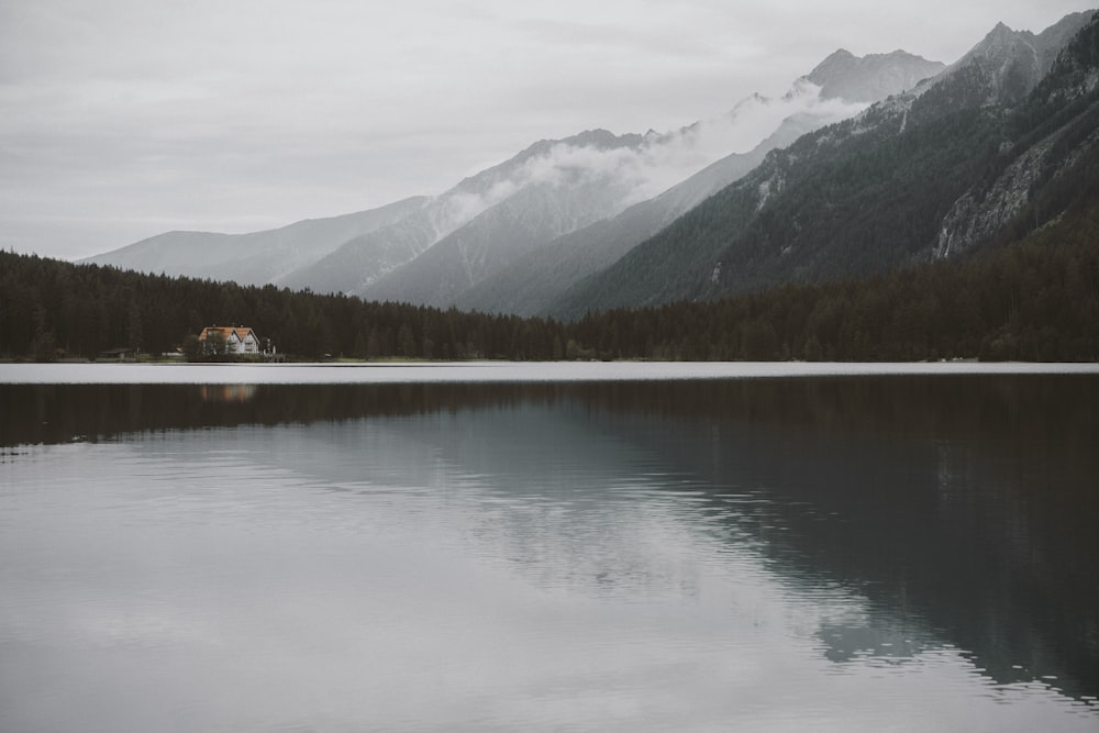 lake near green trees and mountain during daytime