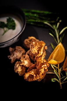 A plate of crispy cassava fries garnished with fresh herbs and a side of dipping sauce.