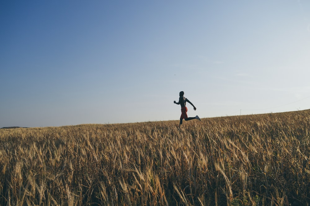 man in black jacket and black pants running on brown grass field during daytime