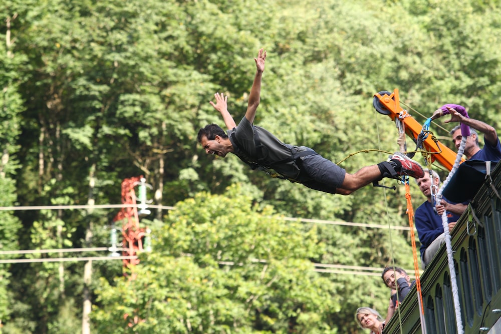 man in black t-shirt and blue denim jeans jumping on mid air during daytime