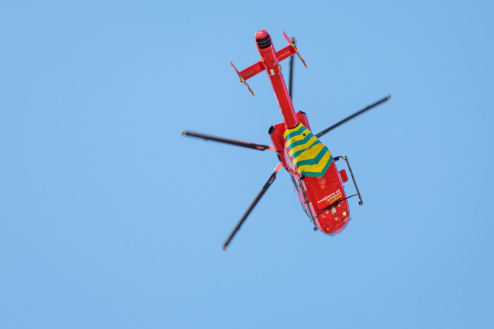 red and yellow helicopter flying in the sky