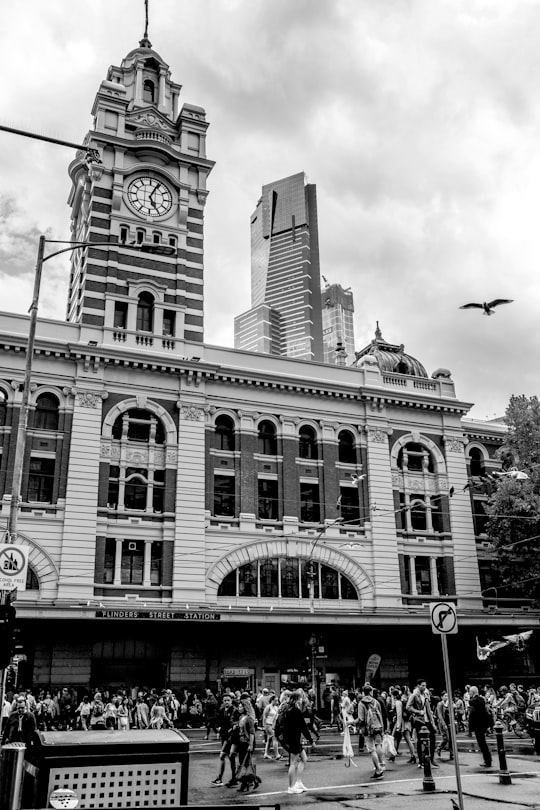 grayscale photo of concrete building with clock in Flinders Street railway station Australia
