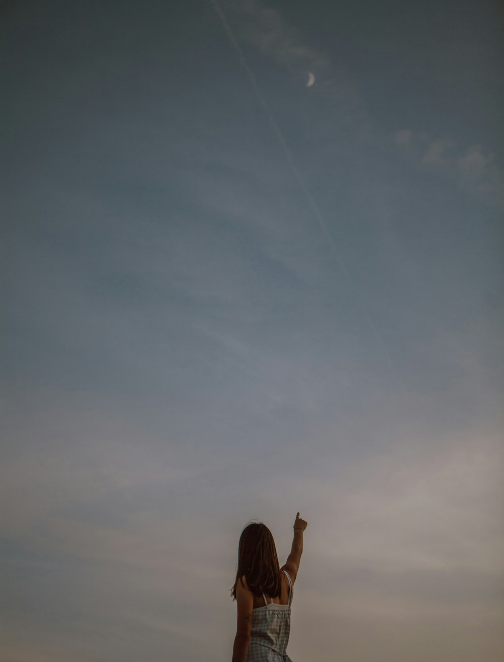 persona che alza la mano destra sotto il cielo blu durante il giorno