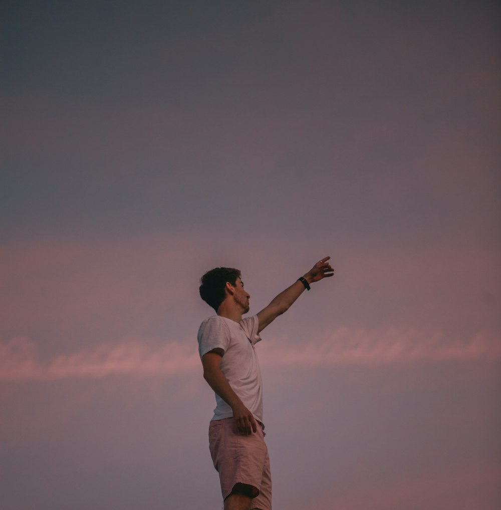 man in white t-shirt and brown pants standing on brown field during daytime