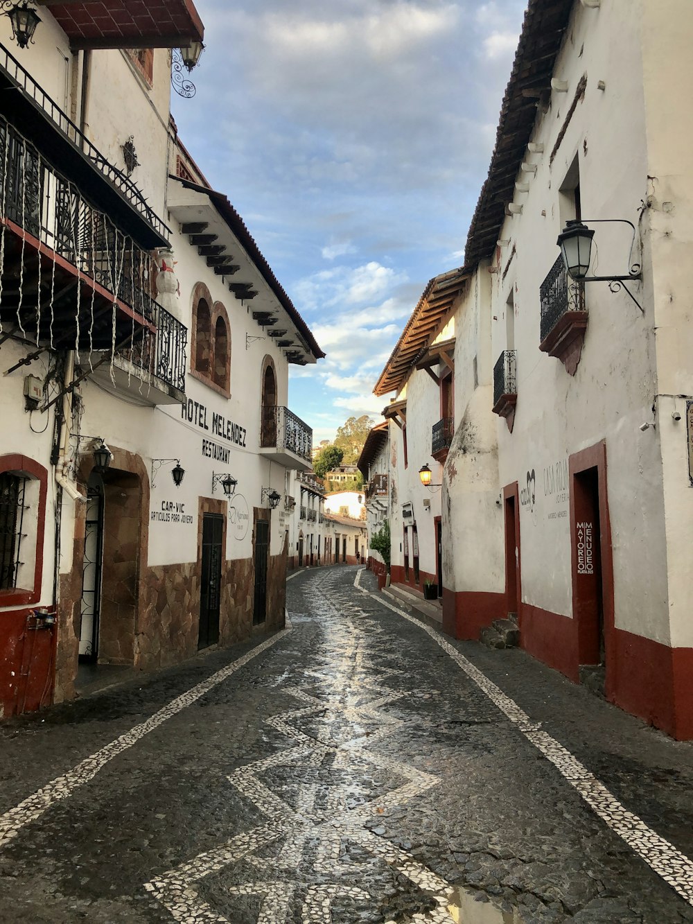 rua vazia entre casas de concreto sob o céu azul durante o dia