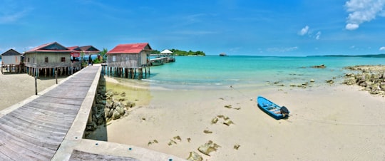 red and white wooden house on beach shore during daytime in Koh Rong Cambodia