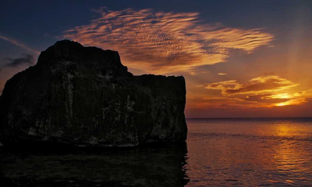 brown rock formation on sea during sunset