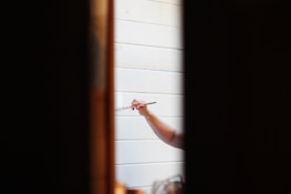 Professional painter using precise brushwork on door trim in a bright apartment unit.