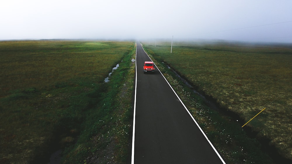 black asphalt road between green grass field during daytime