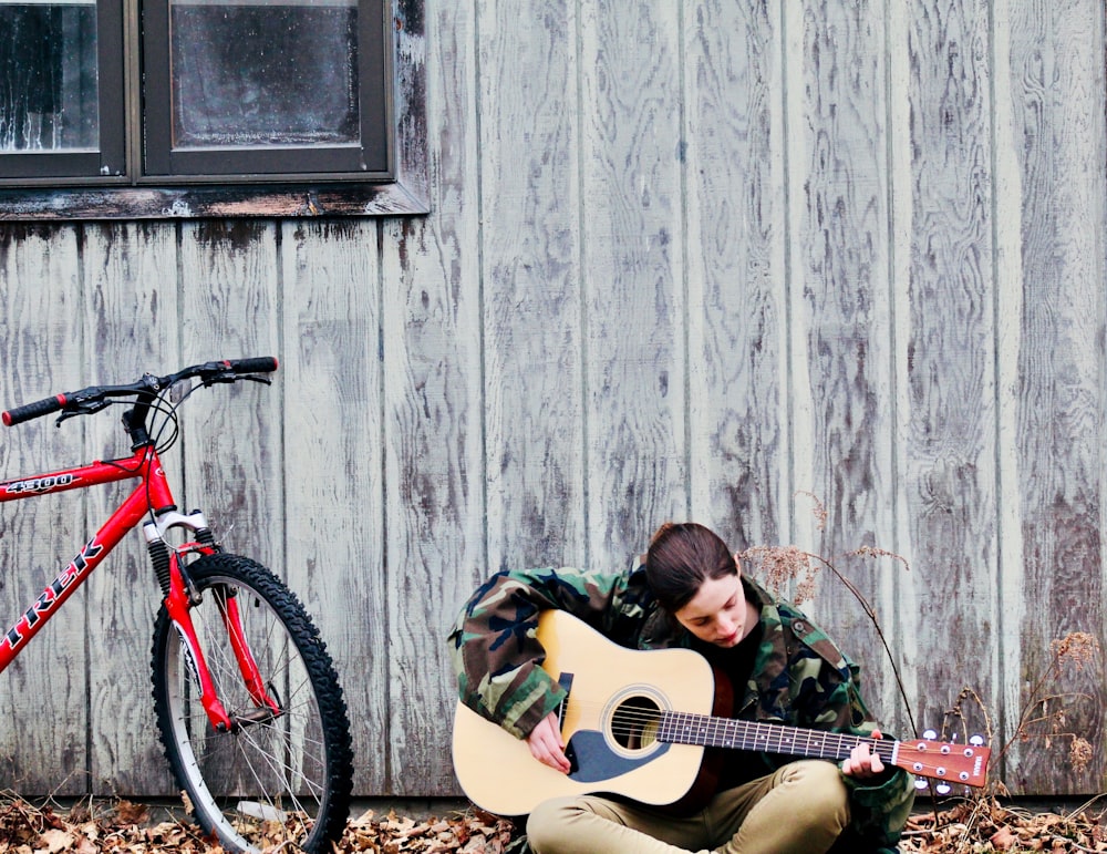 man in black shirt playing brown acoustic guitar