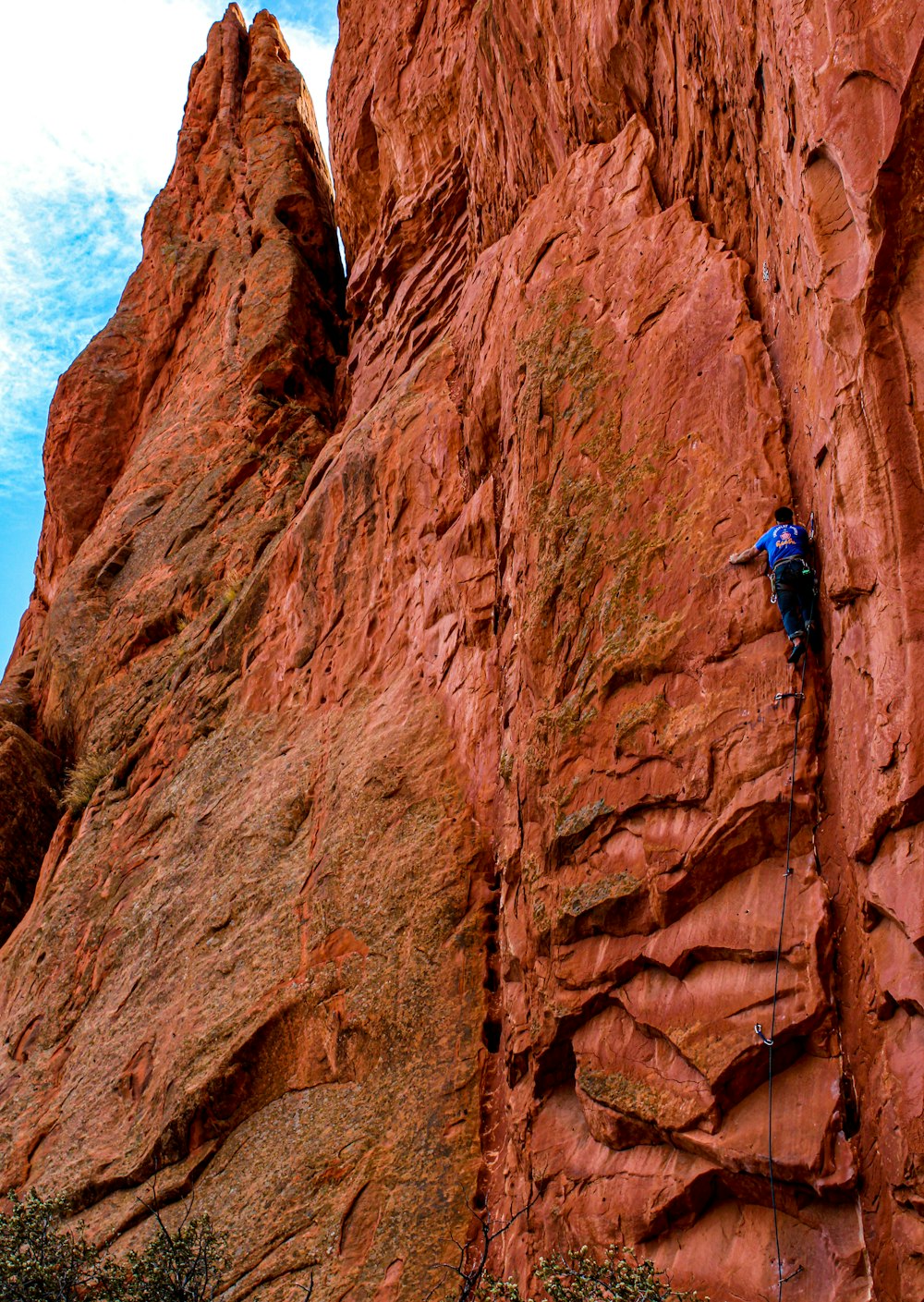 man in blue jacket climbing brown rock mountain during daytime