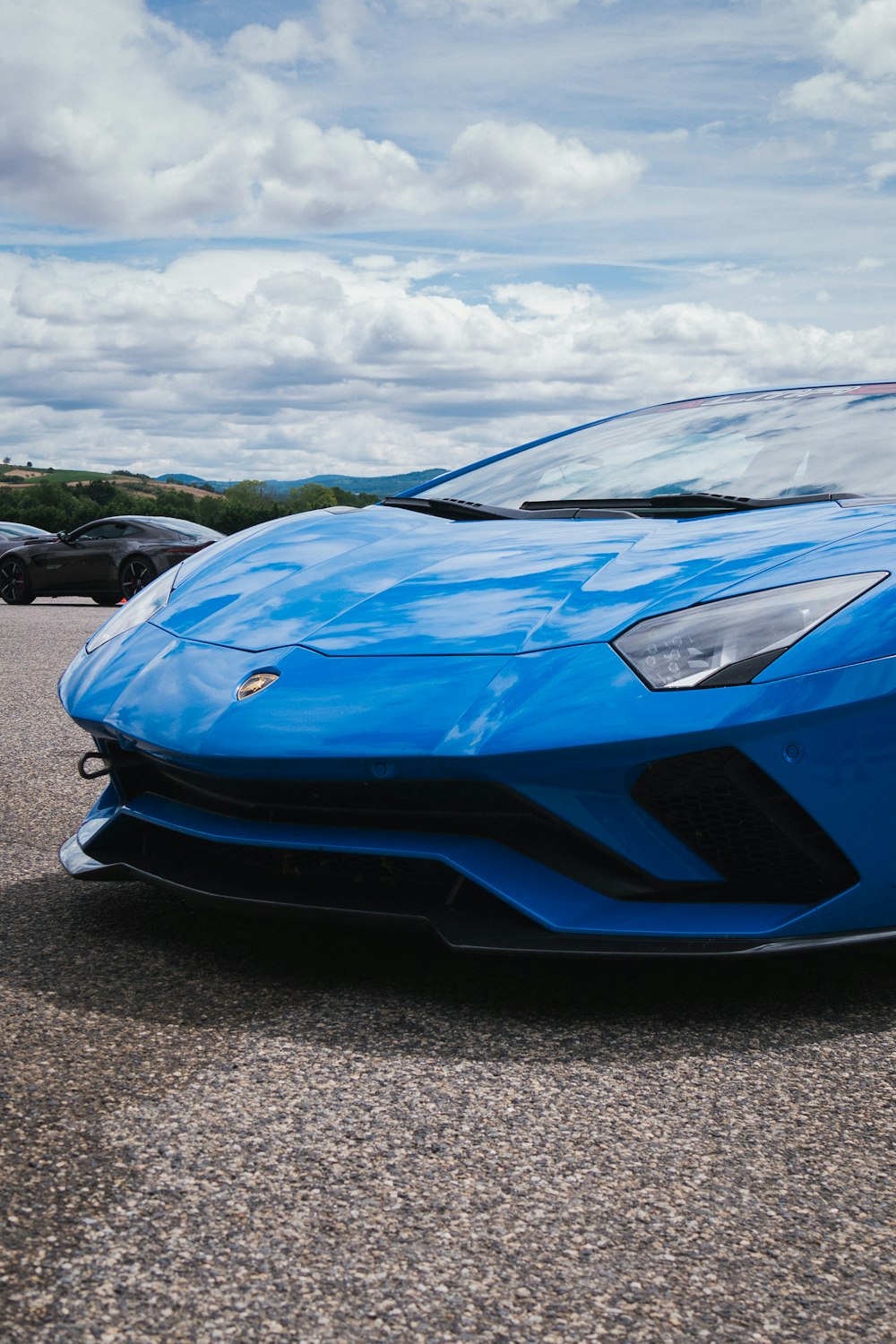 blue ferrari sports car on gray asphalt road during daytime