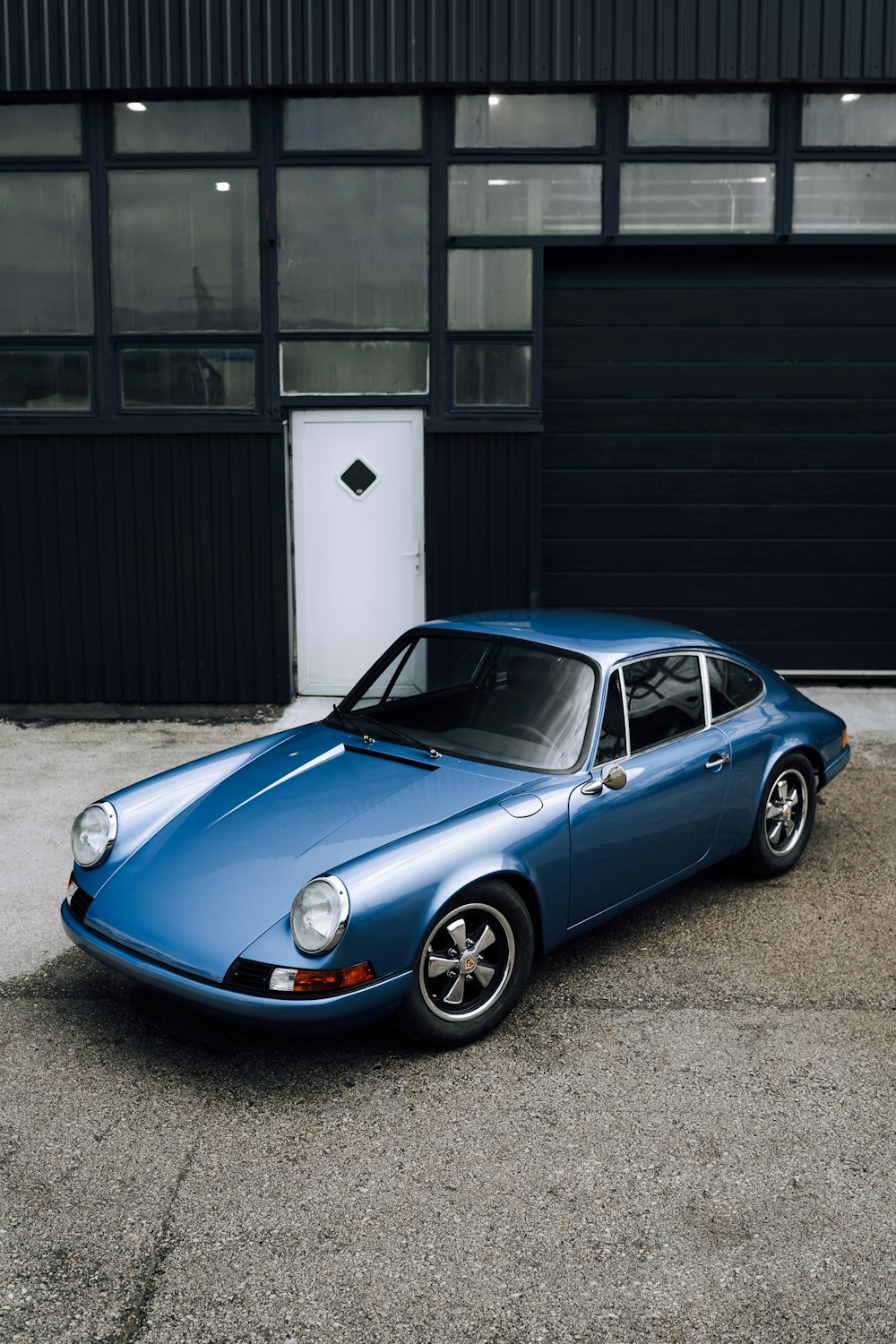 Porsche 911 bleue garée devant un bâtiment blanc