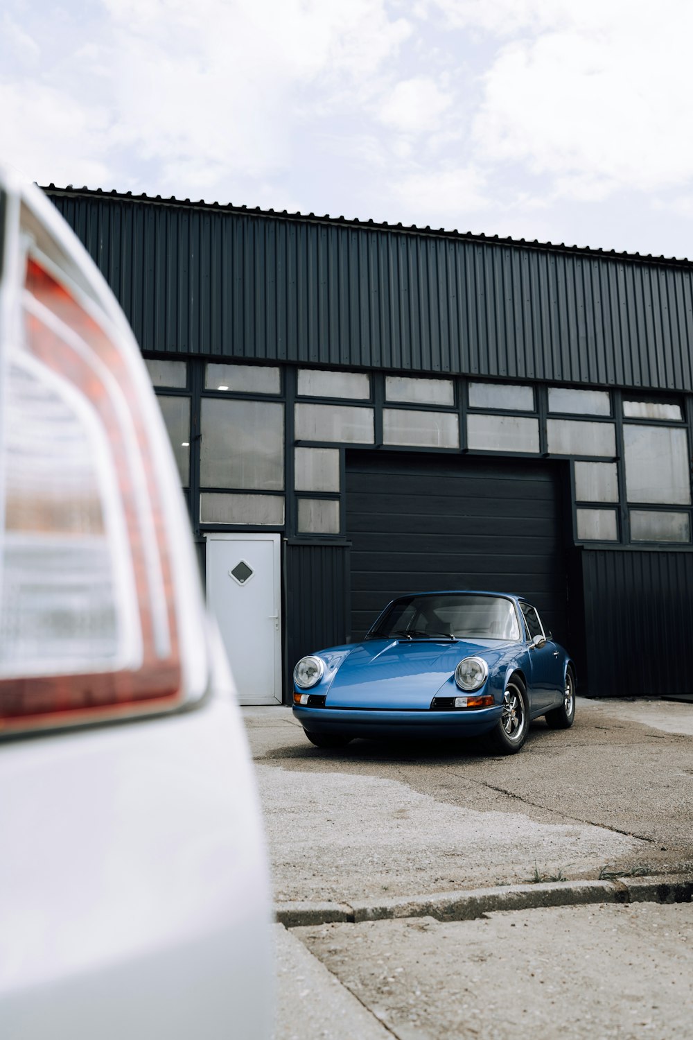 blue porsche 911 parked in front of building