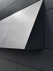 Close-up of a white EPS foam cornice with a smooth, reinforced coating installed on a sleek modern building facade.