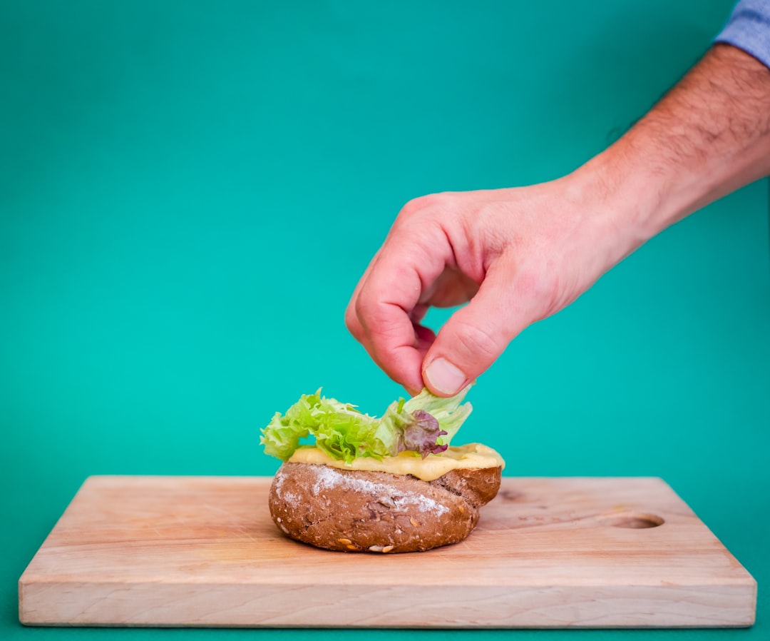 person holding burger with lettuce and tomato