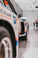 A side view of a row of motorsport vehicles lined up in the aga motorsports workshop.
