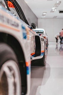 A side view of a row of motorsport vehicles lined up in the aga motorsports workshop.