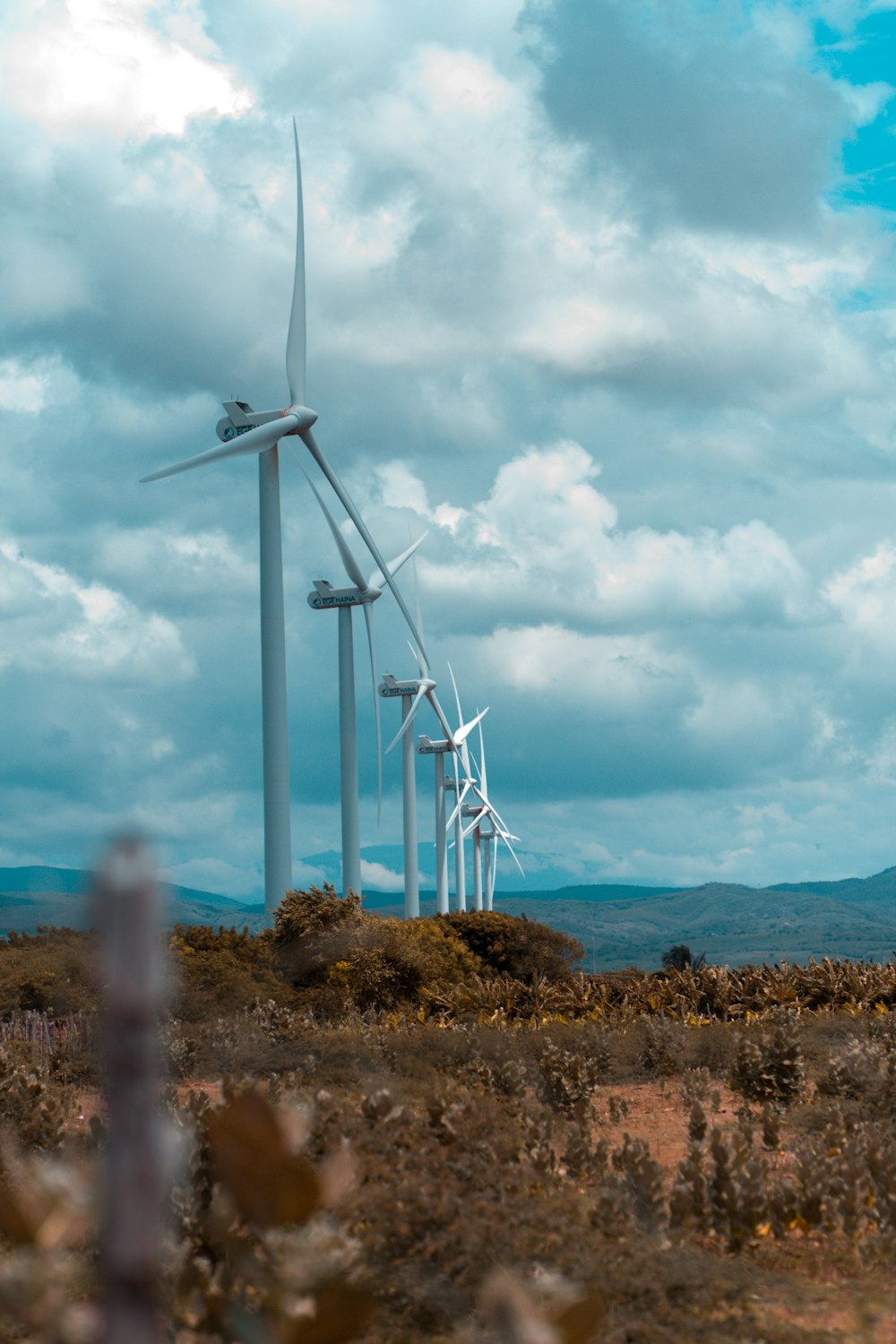 white wind turbines on green grass field under white clouds and blue sky during daytime