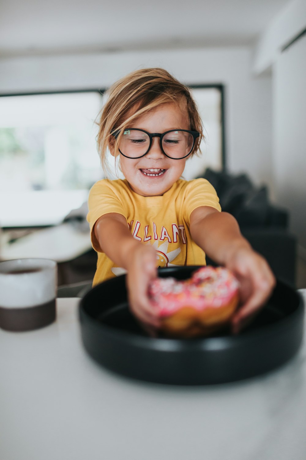 girl in yellow crew neck t-shirt wearing eyeglasses sitting on chair