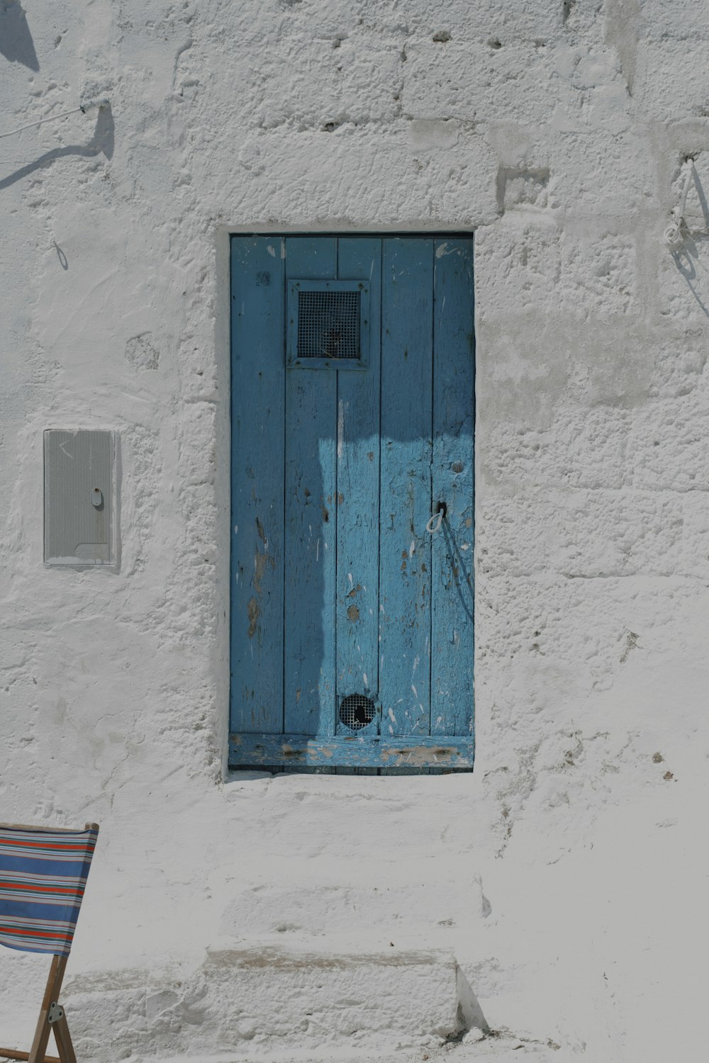 puerta de madera azul sobre pared de hormigón blanco