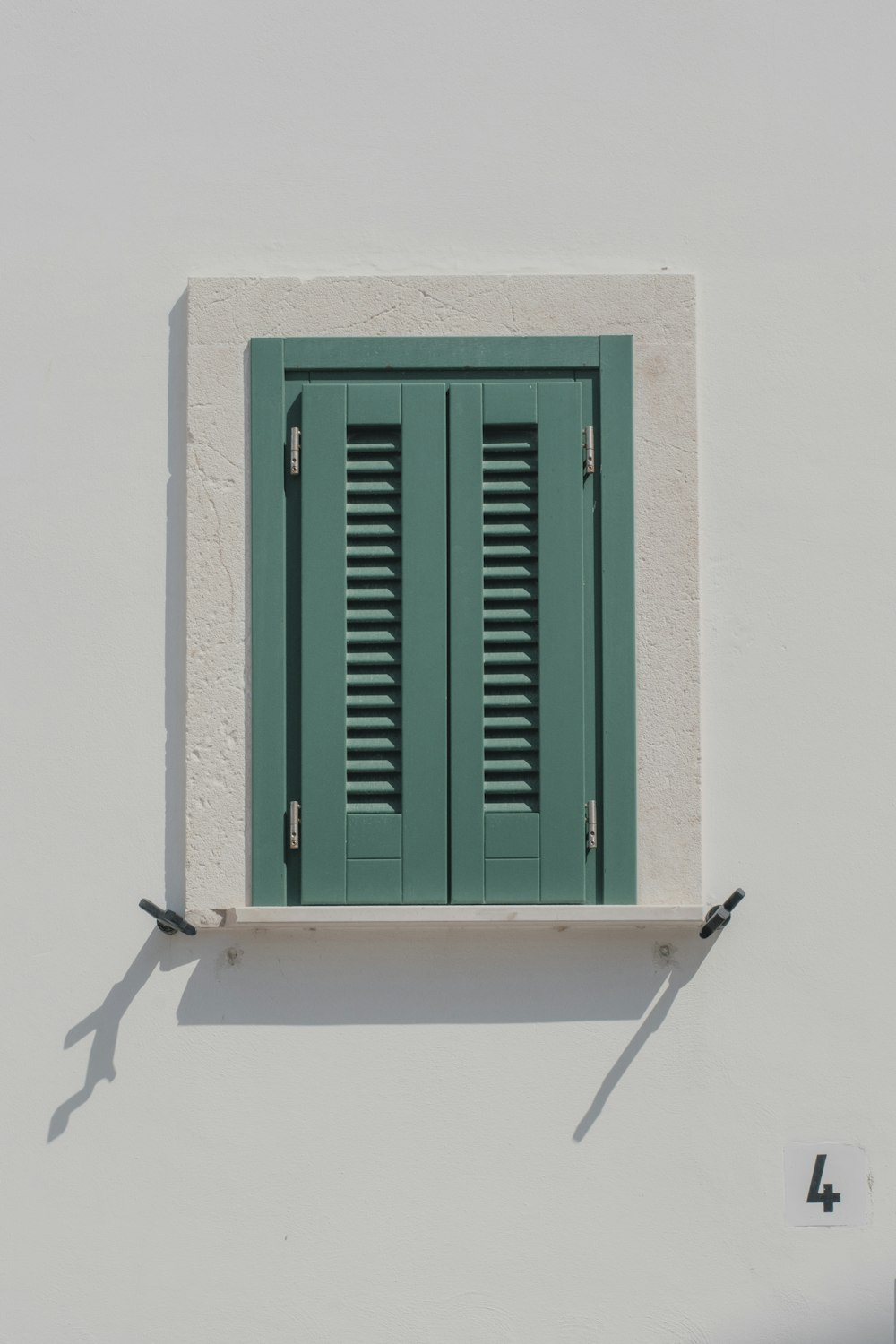 ventana de madera verde sobre pared blanca