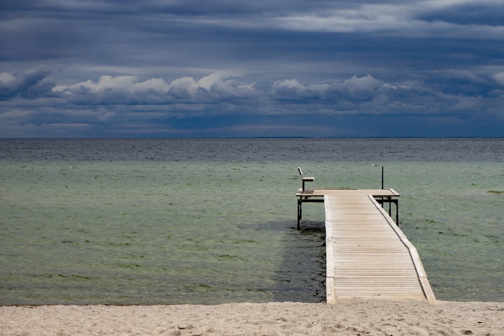 brown wooden dock on sea under blue sky during daytime