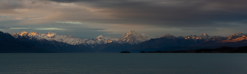 snow covered mountain near body of water during daytime