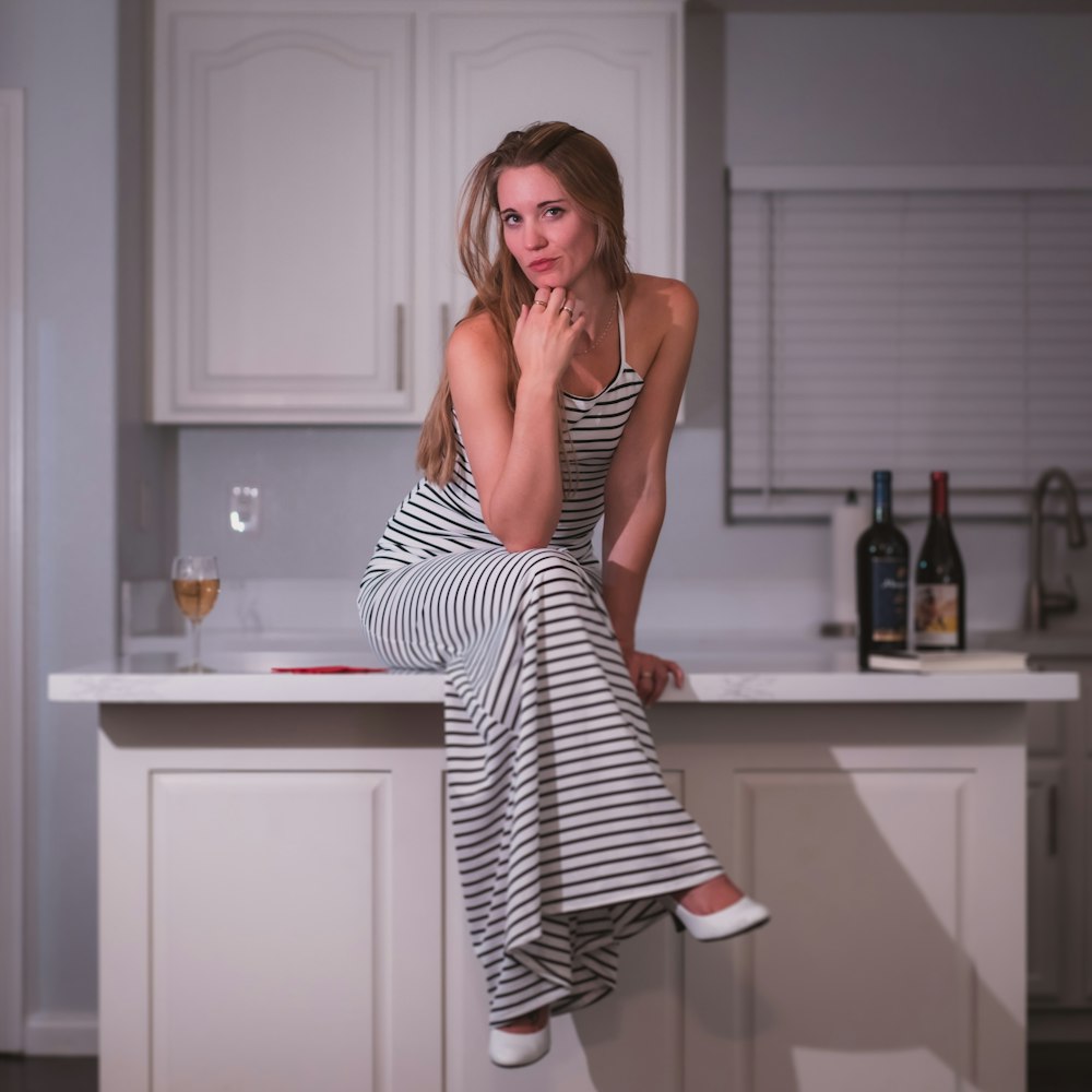 woman in black and white stripe dress standing beside white wooden table