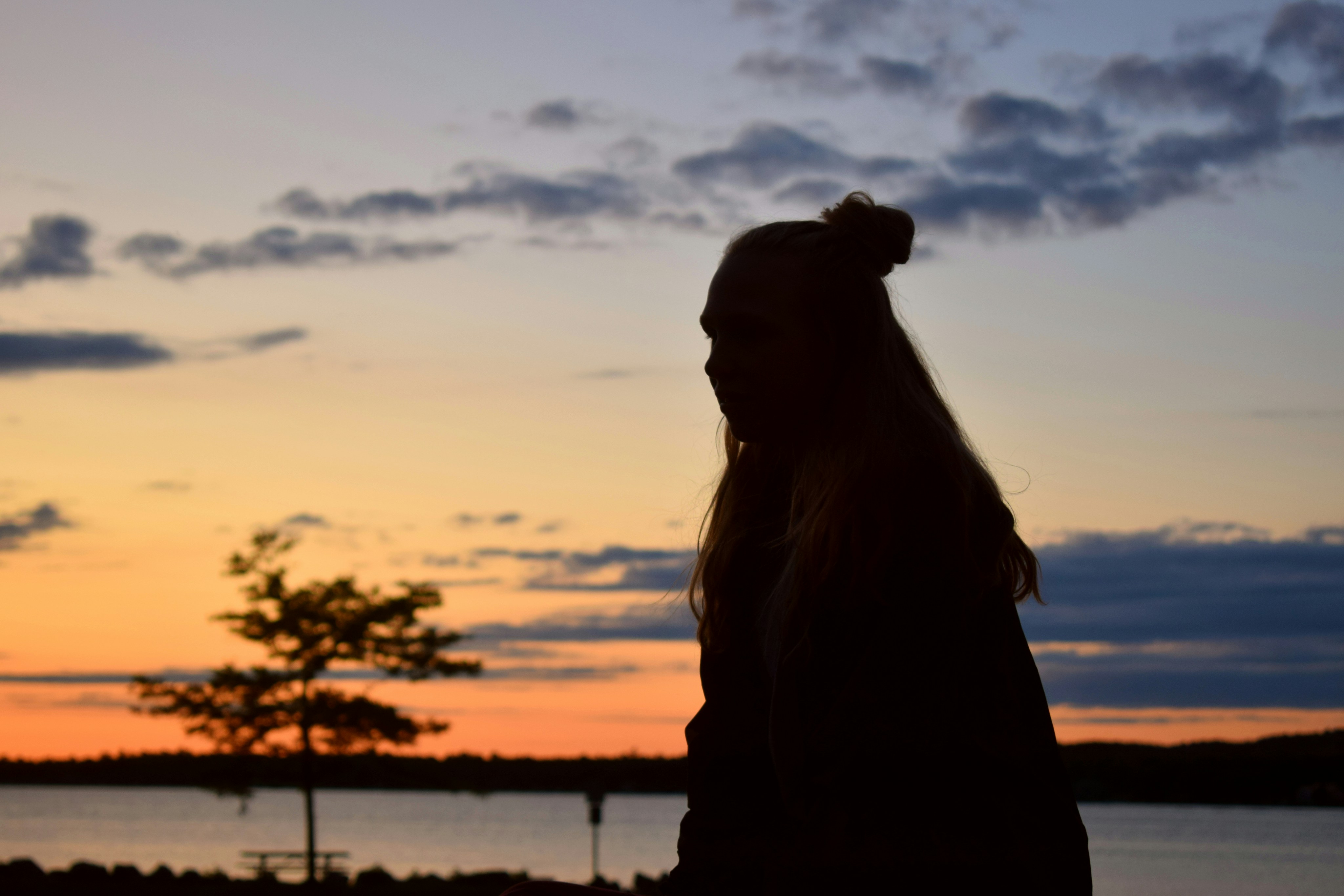 Silhouette of woman standing near body of water during sunset photo ...