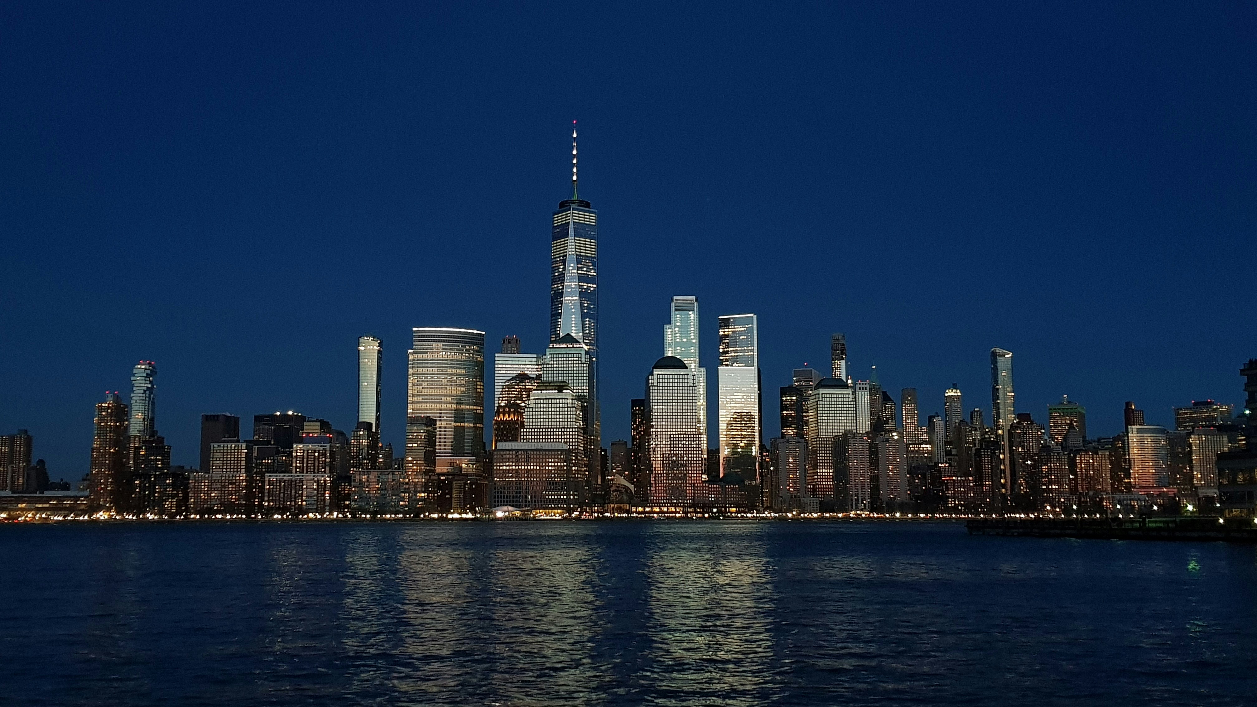 city skyline across body of water during night time