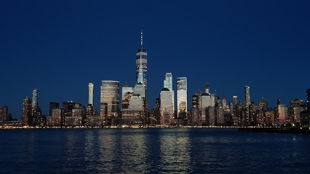 city skyline across body of water during night time