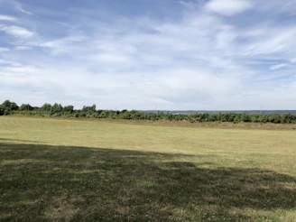 A serene open plot of land ready for building, with clear skies and green grass.
