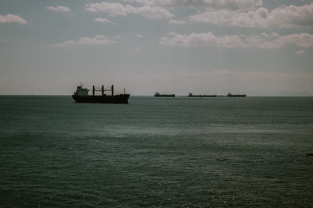 black ship on sea under white clouds during daytime