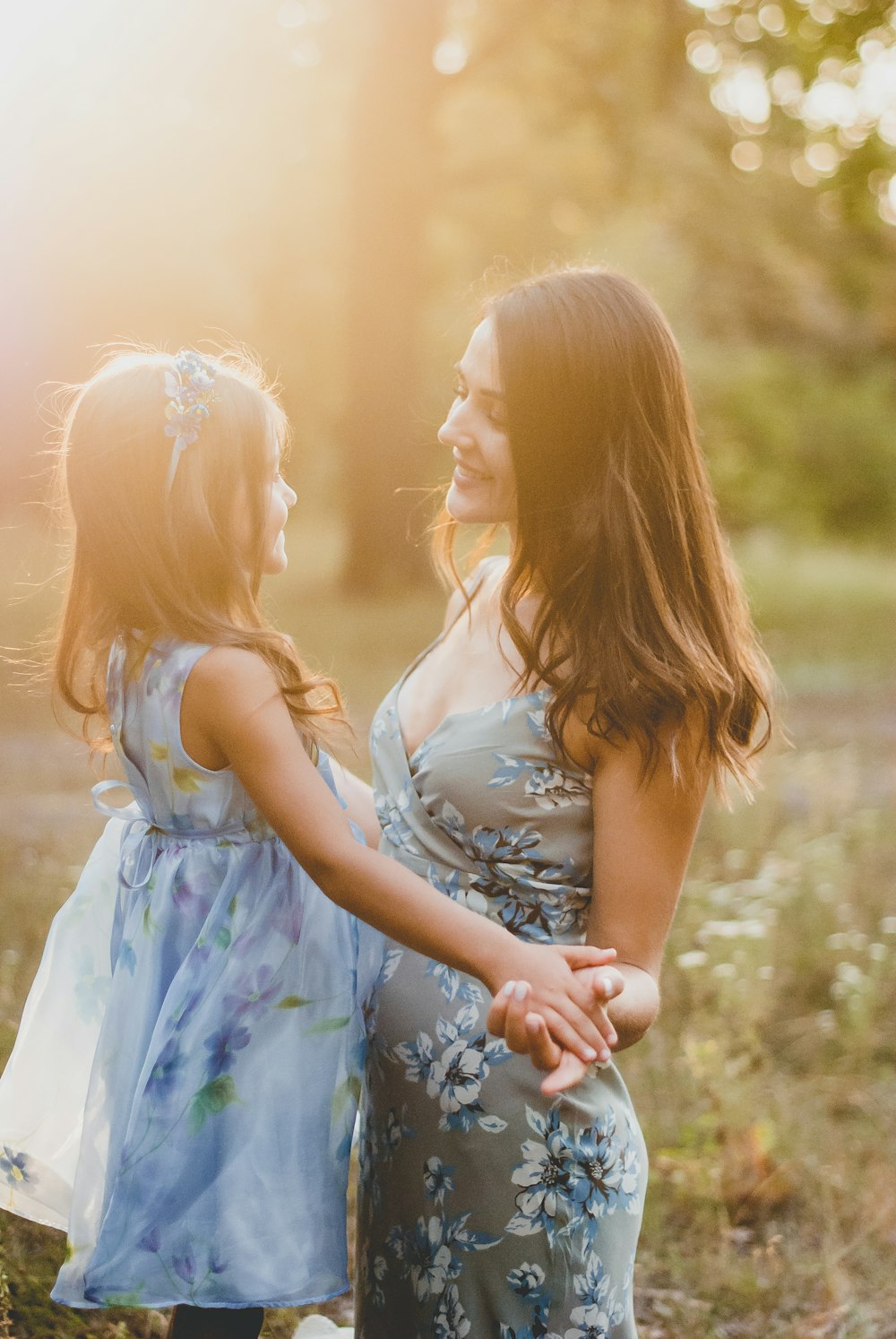 2 girls in white and blue floral dress standing on green grass field during daytime