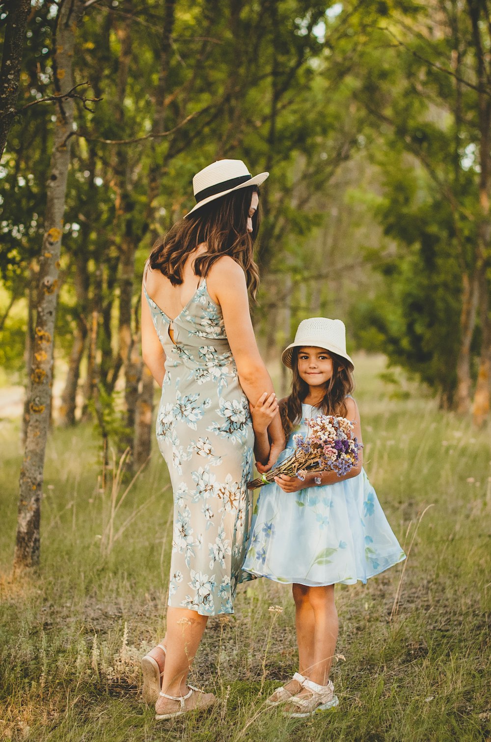 woman in white and blue floral dress standing on green grass field during daytime