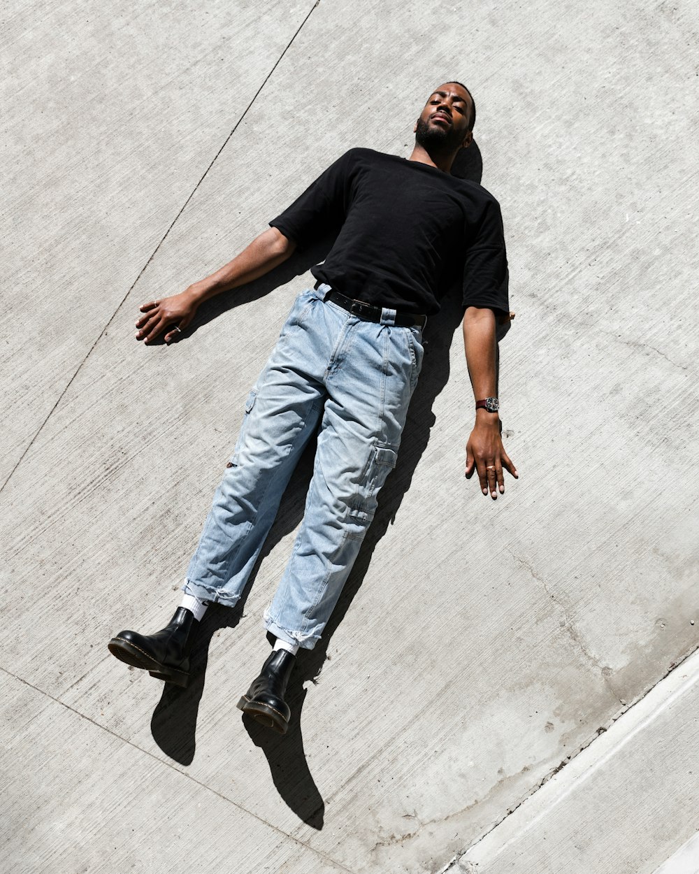 man in black t-shirt and blue denim jeans walking on gray concrete floor during daytime