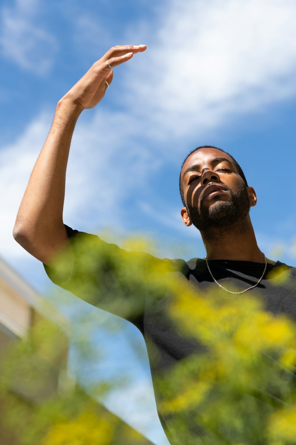 man in yellow and black crew neck shirt raising his right hand