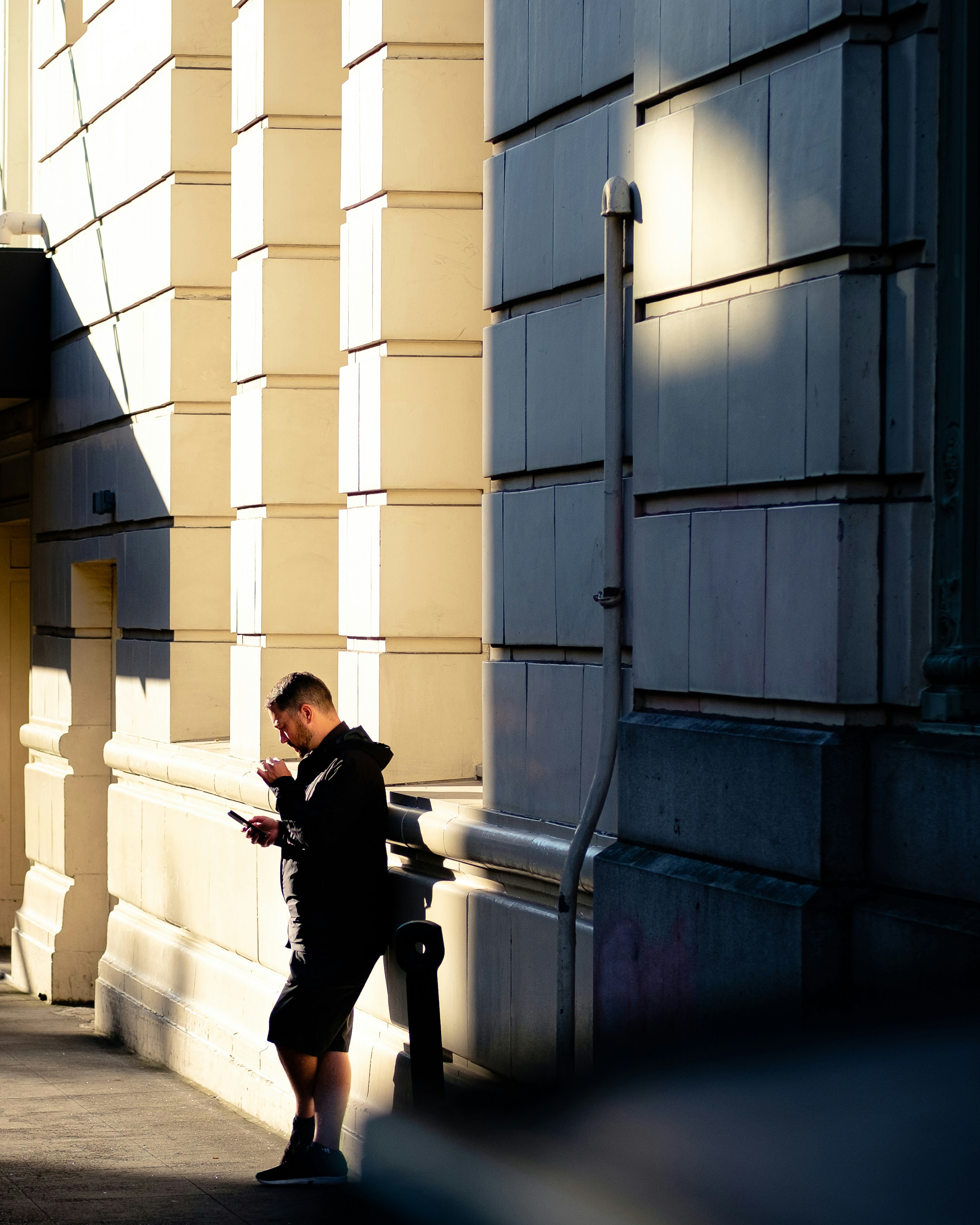 woman in black shirt and black pants sitting on white concrete wall during daytime