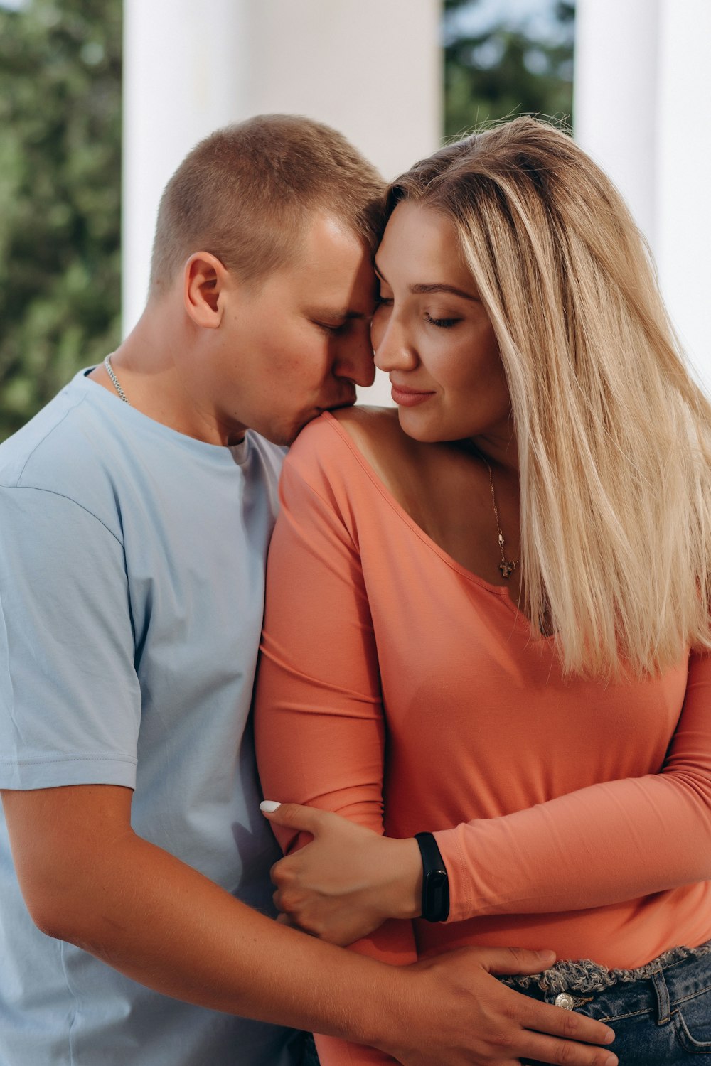 man in blue polo shirt kissing woman in orange dress