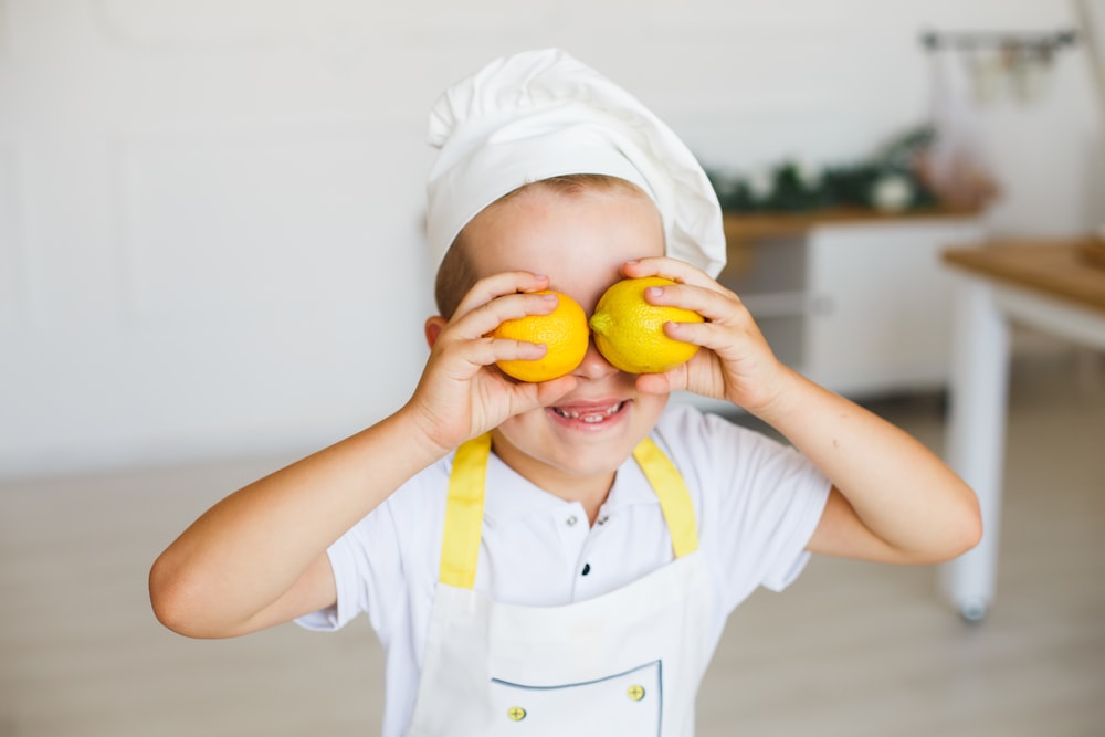 黄色い果物を持つ白いポロシャツの子供