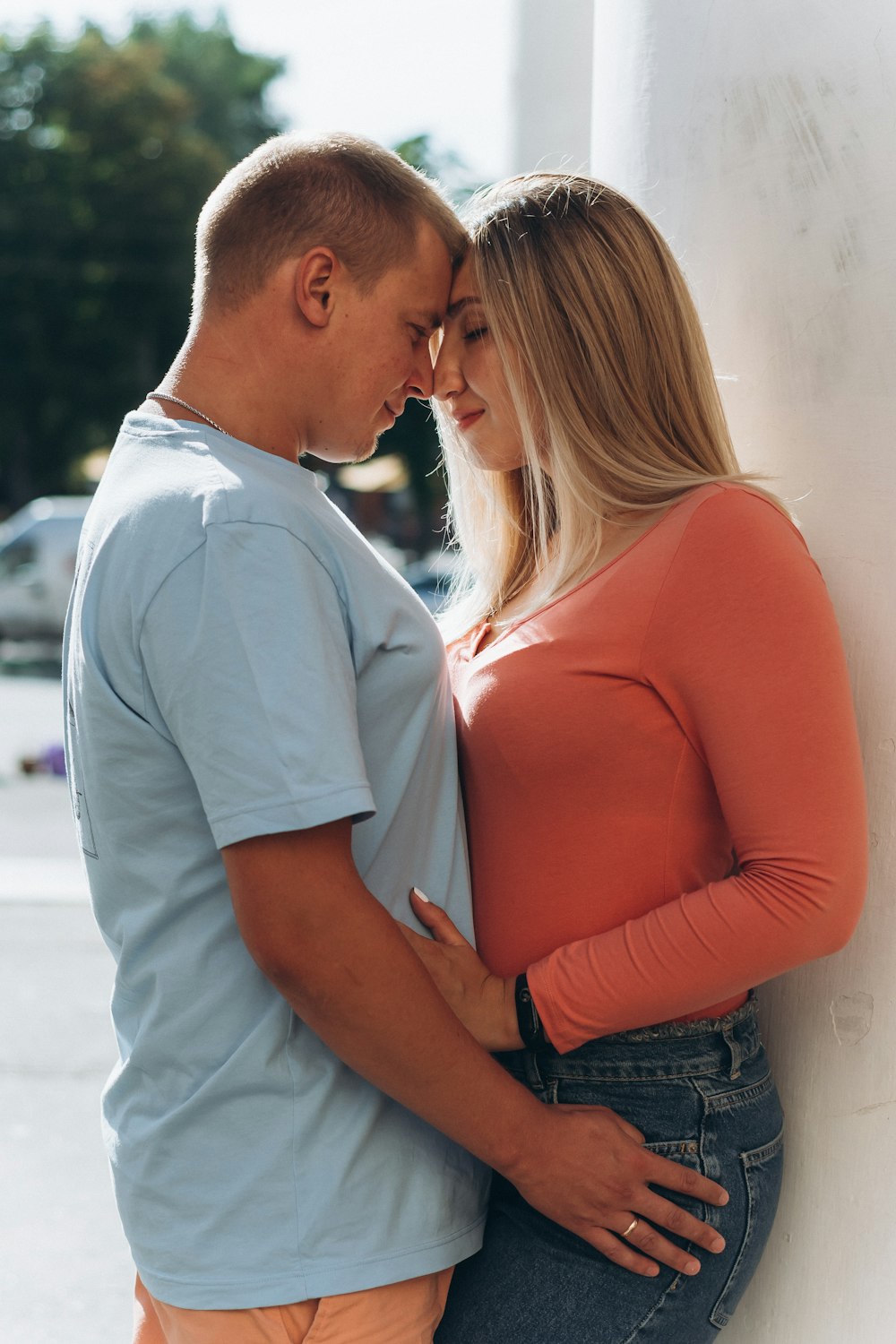 man in white polo shirt kissing woman in orange long sleeve shirt