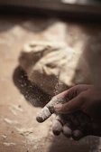 Artisan pizza being hand-stretched with visible texture of the dough and flour dust.