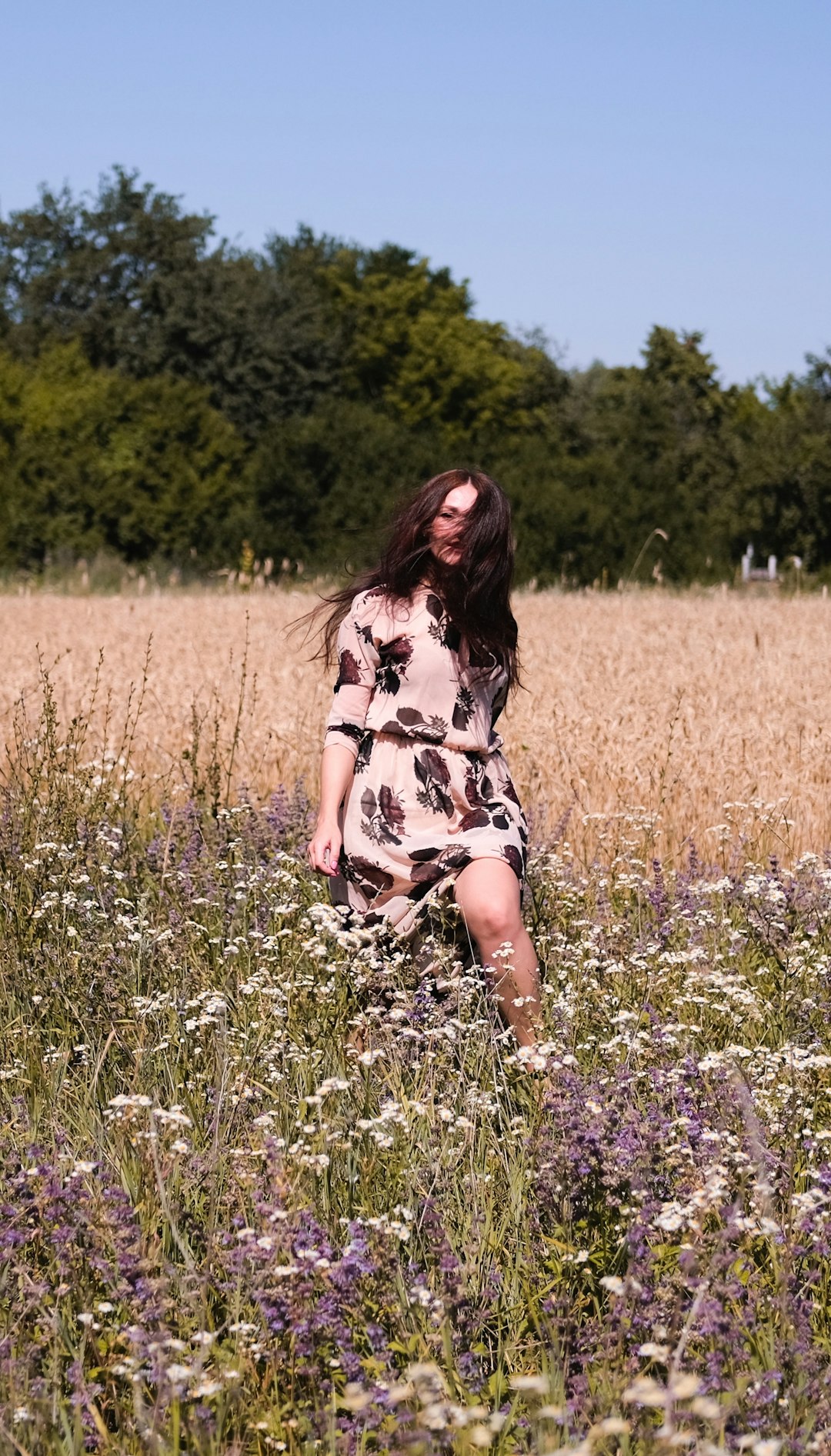 woman in black and white floral dress standing on green grass field during daytime