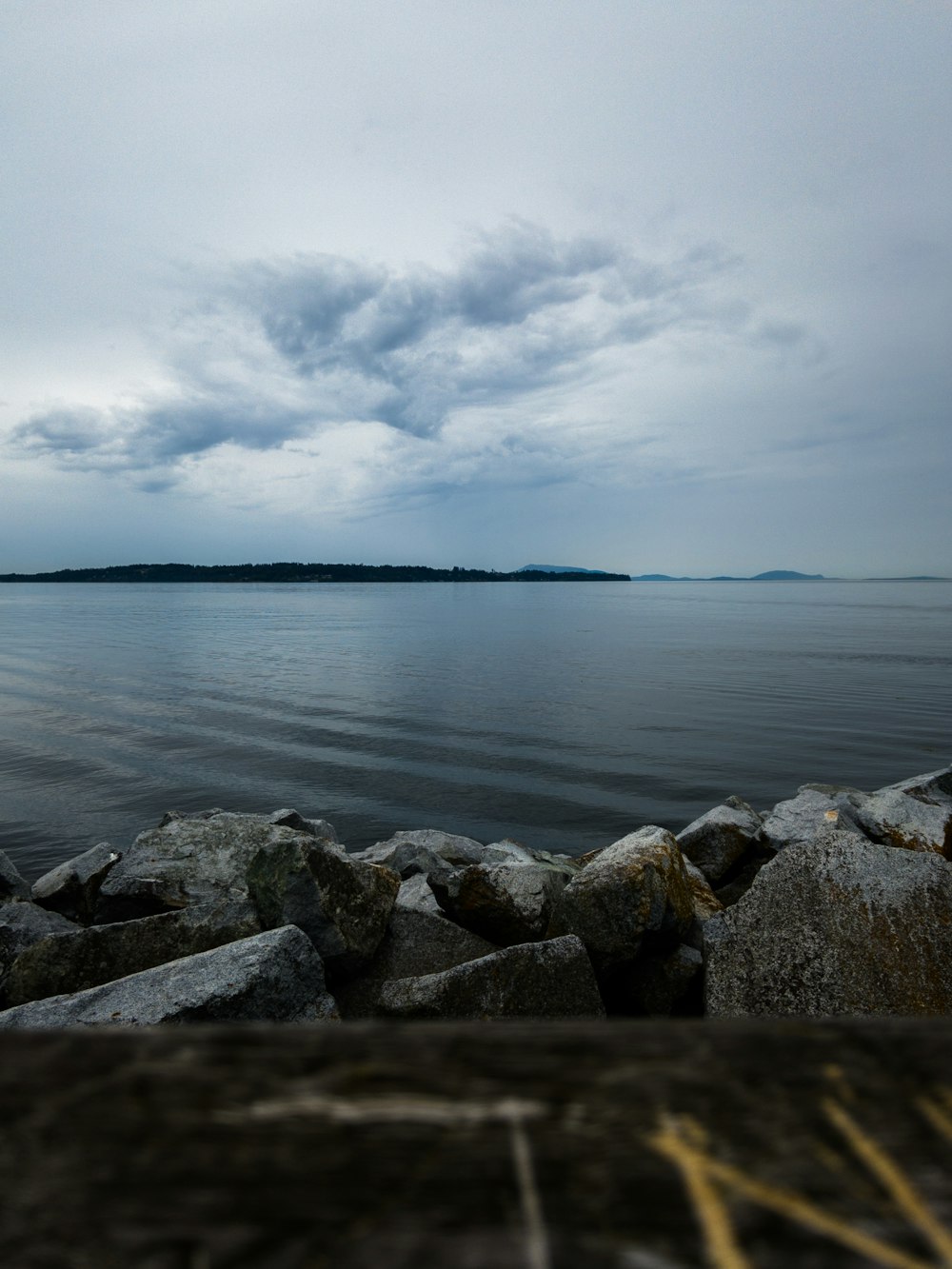 gray rocks near body of water under cloudy sky during daytime