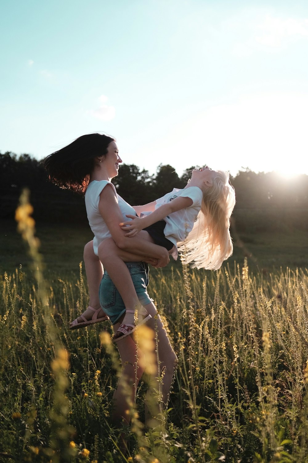 woman in white tank top and blue denim shorts standing on green grass field during daytime