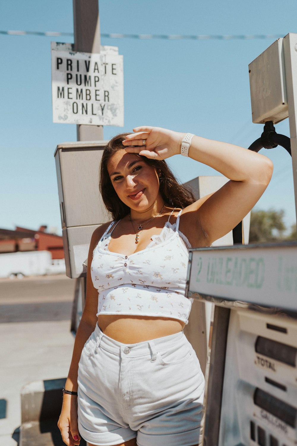 woman in white crop top and white denim shorts holding gray box